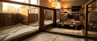 Modern hostel dormitory with wooden bunk beds and warm lighting creating cozy shared accommodation space for budget travelers and backpackers.