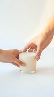 Two hands holding a white soy candle in a clear glass jar on a light background, evoking warmth, care, and mindful living.