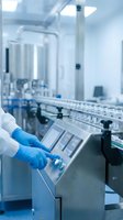 Scientist in blue gloves operating laboratory analyzer equipment in sterile pharmaceutical or medical research facility with automated sample processing system.