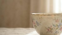 Vintage floral ceramic bowl with delicate pink and blue flowers on cream background, rustic kitchen decor for cooking and serving homestyle meals.