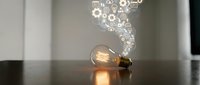 Light bulb with glowing gears and cogs floating above representing innovation, creativity and bright ideas for business solutions and brainstorming concepts.
