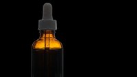 Amber glass dropper bottle with black pipette cap isolated on transparent background, ready for essential oil, serum, and cosmetic product packaging designs, t-shirts, and print-on-demand applications.