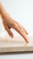 Woman's hand with wedding ring touching marble surface, displaying elegant gesture for jewelry, beauty, and lifestyle marketing campaigns.