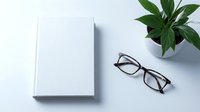 Minimalist workspace with blank white book, eyeglasses and green plant on clean desk. Modern office setup for productivity and reading concepts.