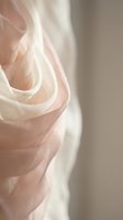 Delicate layers of sheer tulle fabric in soft blush and cream tones create flowing, translucent waves. Suitable for wedding, fashion, textile and design projects.