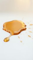 Golden amber liquid droplet with scattered splashes on white background, isolated for skincare, cosmetics, and wellness product design use.