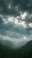 Dramatic storm clouds gather over a lush green mountain valley with sunlight breaking through, creating atmospheric lighting for weather, nature, and landscape design projects.
