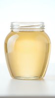 Glass jar filled with golden honey or oil on white background, suitable for food packaging, culinary, and product photography.