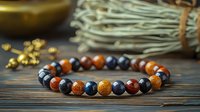 Handmade bracelet with natural stone beads in orange and blue colors on wooden background, spiritual jewelry for meditation and energy healing practices.