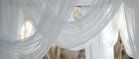 Elegant white flowing fabric drapes creating romantic canopy with soft natural lighting for wedding decor and luxury interior design concepts.