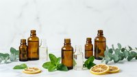 Amber glass bottles with essential oils, fresh mint leaves, dried lemon slices and eucalyptus branches for natural aromatherapy and wellness treatments.