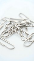 Silver metal paper clips scattered on white background for office supplies and business organization concepts.