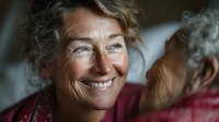 Smiling mature Caucasian woman with gray hair and blue eyes showing genuine happiness and warmth in soft natural lighting for lifestyle content.