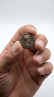 Hand holding ancient Roman bronze coin with emperor portrait for numismatic collection and historical study purposes.