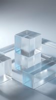 Translucent glass cubes stacked on frosted rectangular blocks, soft blue tones, clean minimalist composition on light gray background.