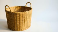 Empty wicker basket with handles on white background for home organization and storage solutions in natural brown color.