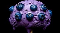 Fresh blueberries on purple ice cream scoop against dark background, macro food photography showing texture and details of frozen dessert and berries.
