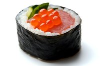 Fresh sushi roll with salmon, red caviar and cucumber on white background, traditional Japanese cuisine closeup macro photography.