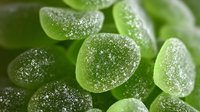 Sugar-coated green jelly candies in macro view, showing texture and crystalline surface. Popular sweet treat for confectionery and dessert designs.