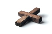 Rustic wooden cross on white background, showing natural wood grain texture and rough surface details. Religious symbol photographed with soft shadow.