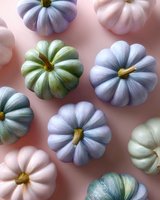 Pastel colored decorative pumpkins in pink, blue and sage green arranged on pink background. Modern festive autumn composition for seasonal decor.