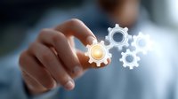 Glowing gear icons floating in air with hand reaching to touch mechanical cog wheel symbols, representing business automation and digital transformation process.
