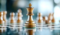 Wooden king chess piece standing on reflective chessboard with blurred white pieces in background, showcasing strategy and leadership concept.
