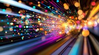 Vibrant light trails and colorful bokeh burst in dynamic motion, creating an abstract pattern of speed, energy and movement against dark background.