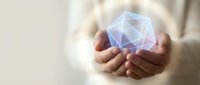Hands holding glowing geometric crystal with polygonal facets and light effects for technology innovation and digital transformation concepts.