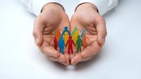Protective hands cupping colorful paper cutout family figures representing care, support, community unity and social responsibility in healthcare concept.
