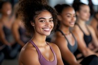 Happy young African American woman smiling in fitness class with diverse group of people exercising together in gym for healthy lifestyle and wellness.