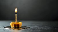 Melting birthday candle on cupcake creates dramatic scene with dripping wax against dark background, single flame glowing in moody atmosphere.