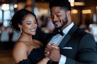 African American couple dancing at wedding reception, bride in black gown and groom in tuxedo share intimate moment with genuine smiles and elegant formal attire.