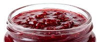 Homemade red fruit jam or preserve in glass jar with visible berries and syrup, suitable for food packaging, recipe blogs, and culinary content.