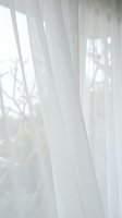 Soft white sheer curtains filtering natural sunlight through window creating gentle shadows and peaceful atmosphere for home interior design.