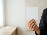 Professional man in dark business attire holding blank white card for mockup, branding, or corporate messaging in modern office setting.