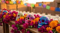 Colorful decorated skulls with bright marigold flowers and candles for Day of the Dead celebration. Traditional Mexican altar setup with vibrant decorations.