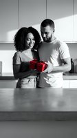 Happy African American couple exchanging red gift box in modern kitchen, romantic moment, love celebration, surprise present giving, relationship goals.