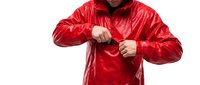 Male adult wearing bright red windbreaker jacket, zipping up front closure with both hands against white background for apparel and lifestyle content.