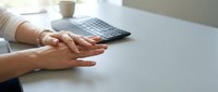 Professional businesswoman hands resting on white desk with calculator in modern office workspace for accounting and financial planning tasks.