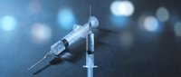 Medical syringes on dark surface with blue bokeh lights background for healthcare and vaccination concepts.