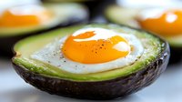 Sunny side up egg baked in fresh avocado half with black pepper seasoning, healthy breakfast option for keto and low-carb diets.