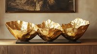 Decorative golden bowls with organic texture and hammered finish displayed on wooden surface against neutral wall with mountain artwork.