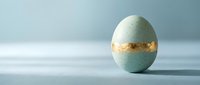 Elegant mint green Easter egg with gold foil band standing upright on clean white surface against soft blue background for spring holiday celebrations.