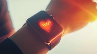 Smartwatch displaying glowing heart rate monitor icon on screen with warm sunset lighting effect, showcasing health tracking and fitness monitoring features.