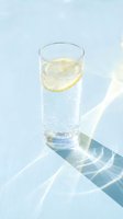 Glass of sparkling water with fresh lemon slice on white surface, ideal for beverage, wellness, and refreshment concepts in advertising and lifestyle design.