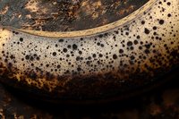 Overripe banana with dark spotted peel showing natural aging process and sugar development, macro photography on dark background highlighting texture and patterns.