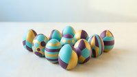 Colorful Easter eggs with geometric patterns and stripes in turquoise, yellow, and purple hues arranged on white surface for holiday celebrations.