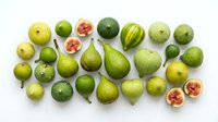 Fresh green figs collection with whole and halved fruits showing pink flesh, arranged on white background for healthy eating and cooking concepts.
