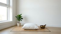 Minimalist meditation space with white cushion on bamboo mat, wooden bowl and green plant by window creating peaceful zen atmosphere for mindfulness practice.